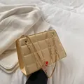 Borsa a tracolla beige trapuntata con catena dorata su sfondo lifestyle accogliente - Giallo