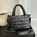 Glänzende schwarze Stepptasche aus Daunen mit breitem Trageriemen und Wellenmuster - Schwarz