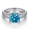 Vue macro d'une bague moissanite bleue 1ct avec monture à griffes et diamants latéraux - Bleu glacier