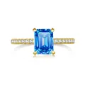 Detailed view of emerald cut blue moissanite ring with gold band and side pavé diamonds - Light Royal Blue