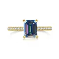 Macro view of emerald cut pink moissanite ring with gold band and side pavé diamonds - Rainbow