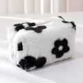 Primer plano de estuche de peluche con estampado floral y cremallera en blanco y negro - Flor negra