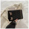 Schwarze Stepptasche mit goldenen Schleifen-Details und elegantem Kettenriemen - Schwarz