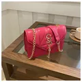 Dettaglio borsa trapuntata fucsia con catena dorata e logo S su un tavolo in legno - rosa acceso