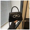 Dettaglio di un'elegante borsa nera con fiocco di strass scintillanti e manico superiore - Nero