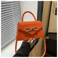 Dettaglio della mini borsa arancione vivace con fiocco di strass e patta a busta - Arancione