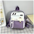 Détails des poches et du charm ours sur le sac à dos bicolore violet et blanc - Violet