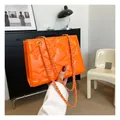 Detail of bright orange crossbody bag featuring quilted star patterns and gold chain strap - Orange