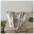 Détail d'un sac fourre-tout en toile blanc cassé avec lettrage FASHION BAG noir et fleurs - Blanc