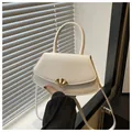 Gros plan d'un sac à main crème avec boucle dorée en forme d'éventail sur un rebord de fenêtre - Blanc