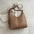 Brown leather moon tote bag with adjustable strap on white textured background - Khaki