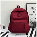 Detail of burgundy waterproof nylon backpack showing side pockets and textured zip pullers - Red