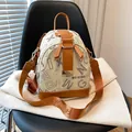 Sac à dos croisé crème et marron avec lettres léopard sur une chaise texturée - Lettres Blanches