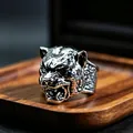 Macro shot of silver panther head ring with retro carving on textured dark wood background - J260 Leopard Head