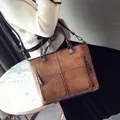Braune Retro-Großraumtasche, getragen als Umhängetasche von Modell im weißen Pullover - Braun