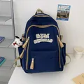 Minimalistischer dunkelblauer Schulrucksack mit beigem SJM-Schriftzug und Anhänger - Blau