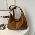 Braune hochwertige Hobo-Tasche mit verstellbarem Riemen auf einem weißen Podest - Hellbraun