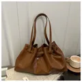 Detail of a brown oil wax leather shoulder bag with glossy finish and ruched texture - Brown