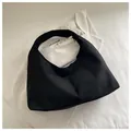 Vista superior de un bolso hobo minimalista de gamuza negra sobre tela de canalé blanca - Negro