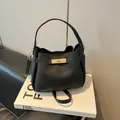 Bolso tipo cubo de cuero granulado negro con cierre giratorio dorado y asa - Negro