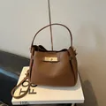 Bolso tipo cubo de cuero marrón oscuro con cierre giratorio de metal dorado elegante - Marrón