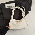Chic cream white shoulder bag featuring a crinkled texture and golden bow detail - White