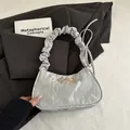 Silberne Hobo-Tasche mit Falten und goldener Schleife über schwarzem Blazer - Silber