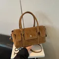 Brown suede vintage handbag with white stitching and detachable strap in a minimal setting - Khaki