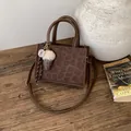 Leopard print tote bag with brown handles and plush charm on a wooden table - Brown