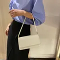 Schicke weiße Unterarmtasche für Damen von einem Model im minimalistischen Stil getragen - Weiß