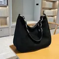 Bolso hobo negro mate clásico con correa de cadena metálica sobre mesa de madera - Negro