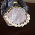 Detail van roze tweed clip portemonnee met parelhandvat en vintage goudkleurig metalen frame - Paars Met Parelgreep