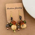 Vista dettagliata dei pendenti vintage fatti a mano con semi naturali e ganci dorati - Stile Nocciolo di Frutta con Perline Ambra (Q-203)