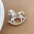 Close-up of a white and gold rocking horse brooch with sparkling crystal rhinestones - White