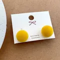 Macro detail of yellow flocked ball stud earrings on a white jewelry display card - Yellow