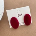 Macro detail of wine red velvet oval stud earrings on branding card with silver 925 post - Oval Design