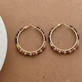 Makroaufnahme von böhmischen Golddraht-Creolen mit braunen Perlen auf strukturiertem Grund - Kaffeebraun