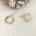Close-up of geometric rattan hoop earrings with white resin studs on a textured background - Hollow Circle Style 6