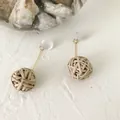 Close-up of elegant straw woven ball earrings with gold-plated rods on natural stone surface - Long Rattan Ball Style 7