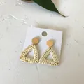 Detail of bohemian triangular woven rattan earrings with golden metallic studs on white stone - Light Color Triangle Rattan