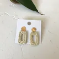 Close-up of bohemian rectangle rattan earrings with golden studs on a white display card - Rectangular Rattan Style
