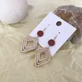 Detail view of bohemian rattan earrings with red discs on warm textured background - Brown Red Disc Large Rhombus Rattan (B17)