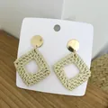 Detail of square woven rattan earrings with golden metal studs on white card display - Light Color Hollow Square Rattan