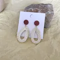 Detail of bohemian red round stud and beige woven teardrop dangle on display card - Dark Red Disc Beige Teardrop Rattan (B38)
