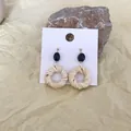Detail of bohemian woven straw earrings with black beads on a natural stone background - Black Oval Bead Off-white Rattan Circle (A17)