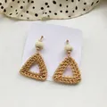 Detailed view of handmade woven rattan triangle earrings with wooden beads on display card - Dark Triangle
