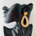 Detail of bohemian rattan drop earrings worn by a model showcasing teardrop weave texture - New Rattan Style 29 (Orange Dome Teardrop Pendant)