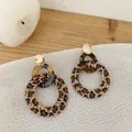Close-up of leopard print straw earrings with golden studs on a rustic wood background - Three-Tier Tortoise Ring Style (Style 3)