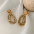 Detail of bohemian rattan drop earrings with round wooden studs on textured linen fabric - Dark Tone Waterdrop