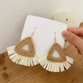 Close-up of handmade triangular rattan earrings with white raffia fringe on wood background - Dark Color Triangle Rattan (A87)